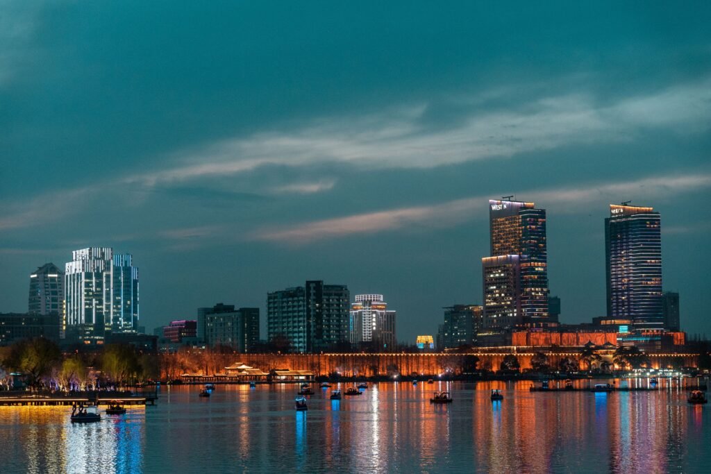Beautiful urban skyline at dusk, reflecting on calm water with vibrant city lights.