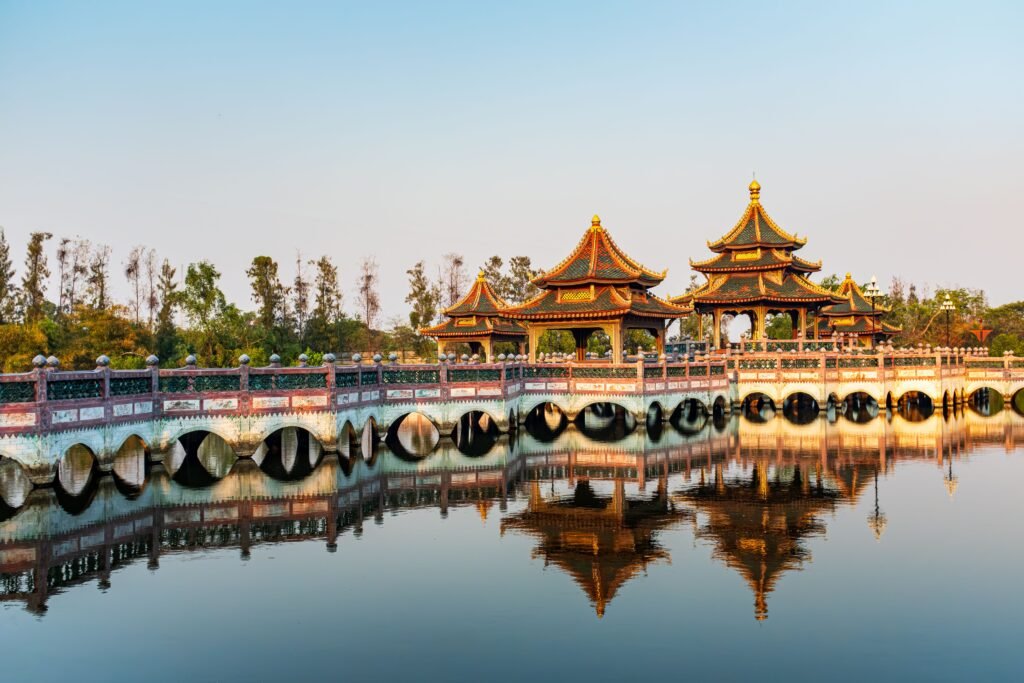 Captivating reflection of a traditional Thai temple and bridge in Bangkok at sunrise, highlighting cultural beauty.