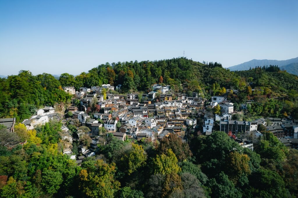 Picturesque Chinese village surrounded by vibrant greenery in the mountains. Captured during the day with clear skies.