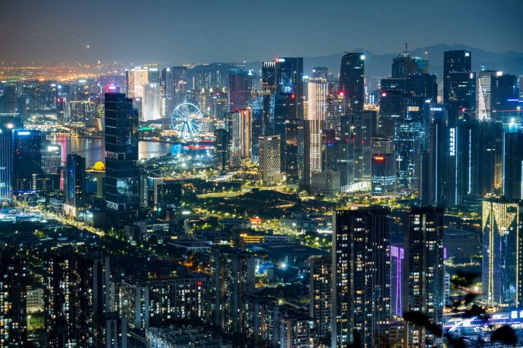 Dazzling city skyline illuminated at night showcasing modern skyscrapers and a Ferris wheel.