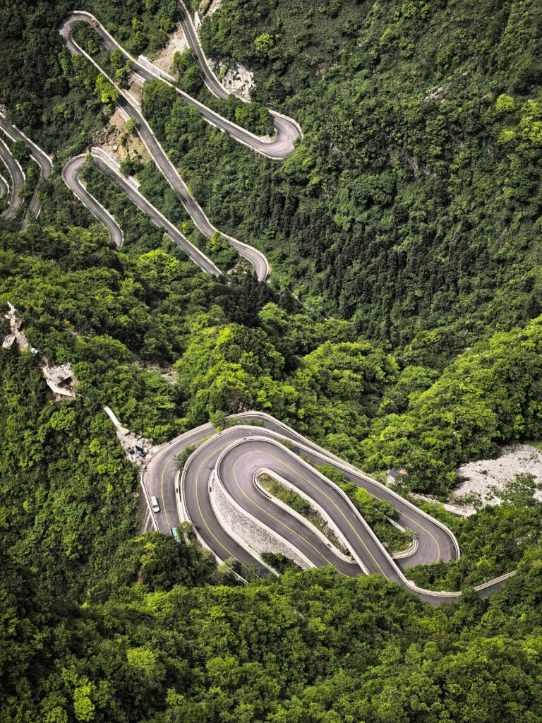 Breathtaking aerial shot of a winding road through lush greenery.