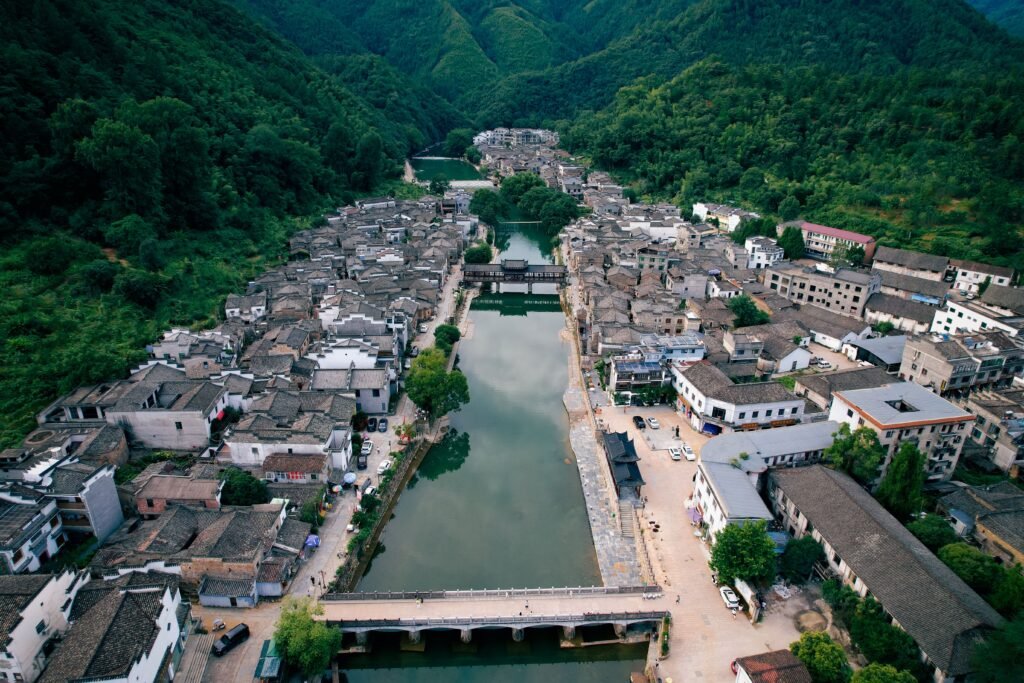 Aerial view of a historic village in Jiangxi, China surrounded by lush greenery and a tranquil river.
